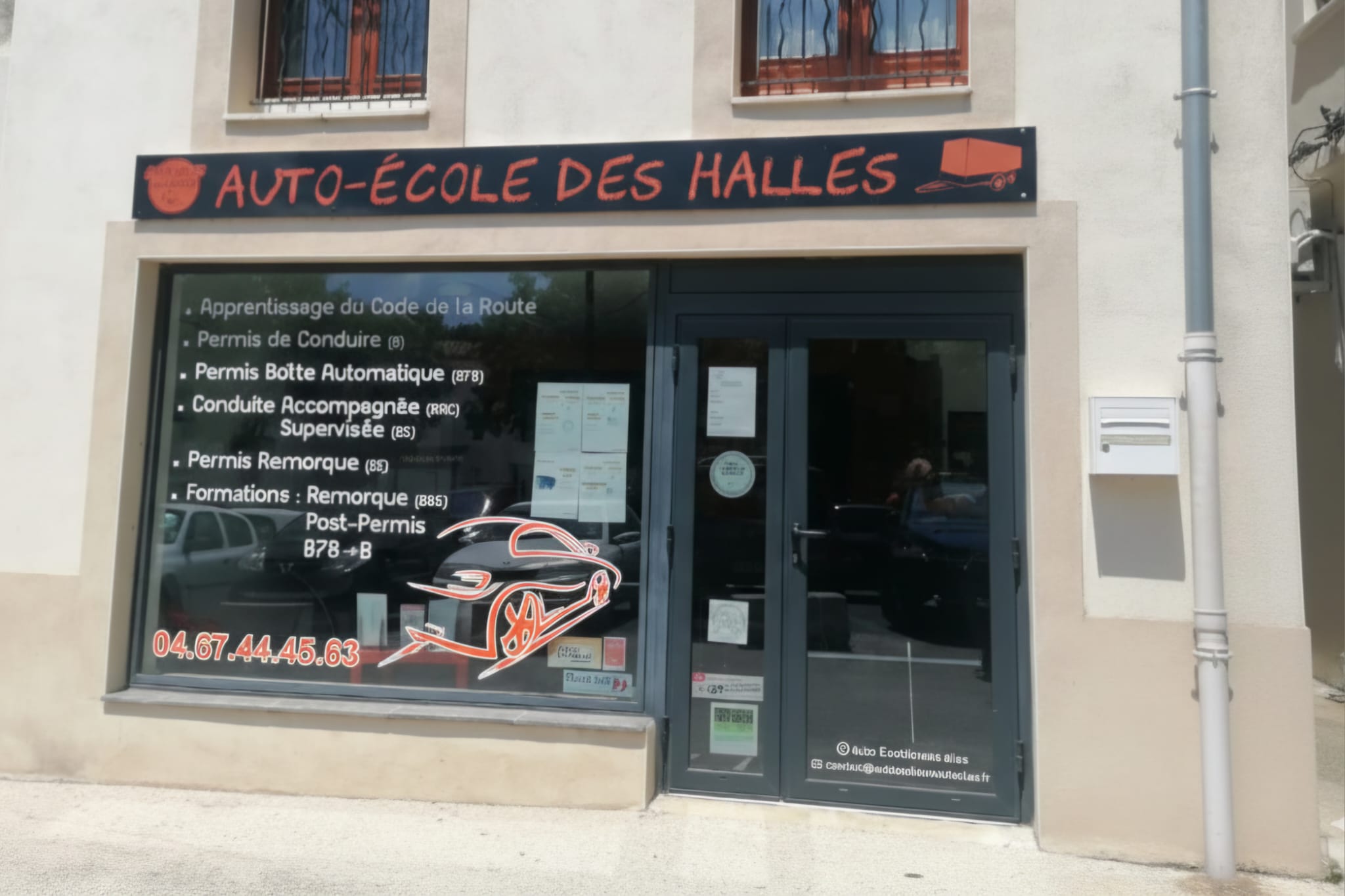Devanture de l'Auto-école des Halles, rue de la Halle à Lodève, avec ses véhicules d'apprentissage